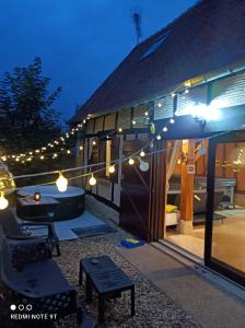 a patio with a table and lights on a house at Sauna & Double Jacuzzi intérieur et sous les étoiles 1h30 Paris in Ladon