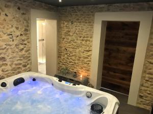 eine große Badewanne in einem Zimmer mit einer Steinmauer in der Unterkunft Gite de la Prée SPA luxe proche Giverny et bord de l'Eure in Ménilles