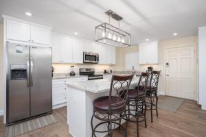 a kitchen with a stainless steel refrigerator and bar stools at Shores Club 703 in Daytona Beach +62 photos