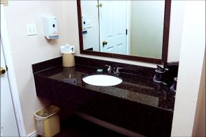 baño con lavabo y espejo grande en Antler Motel en Kemmerer