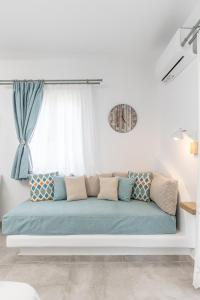een blauwe bank in een witte kamer met een raam bij Arhontiko in Naxos Chora