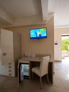 Habitación con escritorio y TV en la pared. en B&B Villa Lisa, en Corigliano Calabro