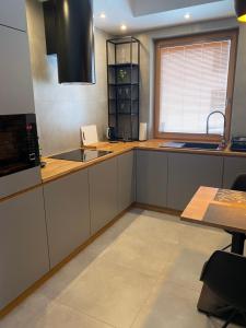 ワルシャワにあるApartament Rzekotka Zielona Dereniowa 60の白いキャビネット、シンク、窓付きのキッチン +5枚の写真