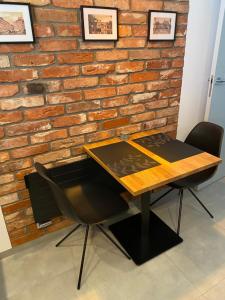 a wooden table and chairs in front of a brick wall at Apartament Rzekotka Zielona Dereniowa 60 in Warsaw