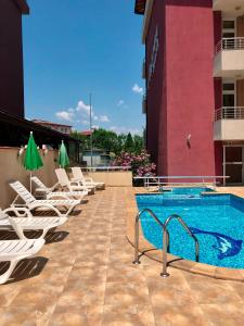a pool on the roof of a building with lounge chairs at Hotel Ancora Beach in Primorsko