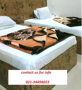 Rehaish Inn Model Colony في كراتشي: سريرين في غرفة عليها بطانية