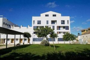 un grande edificio bianco con alberi di fronte di Apartamento Cala Busquets a Ciutadella