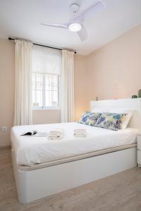 um quarto branco com uma grande cama branca e uma janela em Livemálaga Gordon Home em Málaga
