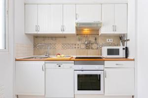 uma cozinha branca com armários brancos e um micro-ondas em Livemálaga Gordon Home em Málaga