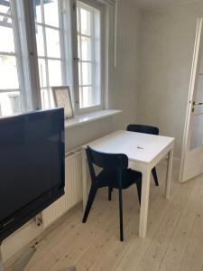 a living room with a white table and a tv at Annex near beach close to Copenhagen in Vedbæk
