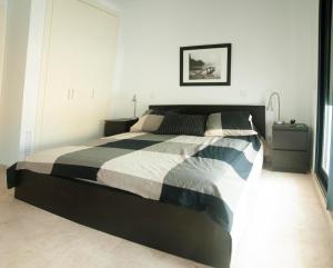 a bedroom with a bed with a black and white comforter at Apartamento Cala Busquets 6 pax in Ciutadella