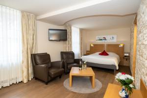 Habitación de hotel con cama, 2 sillas y mesa en La Couronne à Wissembourg, en Wissembourg
