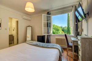 a bedroom with a bed and a window and a desk at Logis Hotel Le Blason de Provence in Monteux