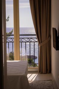 a bedroom with a view of the ocean from a balcony at Vertmont Villa in Sveti Stefan