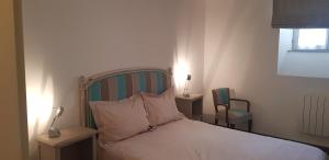 a bedroom with a bed with two tables and a chair at Le jardin de l'horloge in La Rochelle