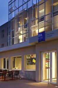 a building with tables and chairs in front of it at ibis budget Saint Pourcain in Saint-Pourçain-sur-Sioule