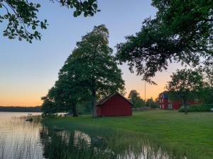 un granero rojo en un campo junto a un lago en Holiday home Tussered Hacksvik, en Håcksvik