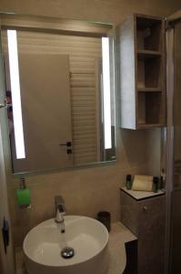 a bathroom with a sink and a large mirror at Seafront Centre Ouranoupoli in Ouranoupoli