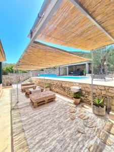 une terrasse avec bancs et une piscine avec un grand parasol dans l'établissement Olive Tree - House with Pool, à Vinišće