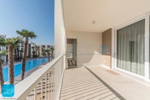 balcón con piscina y palmeras en Residence Wave Plus, en Lido di Jesolo