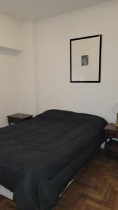sypialnia z czarnym łóżkiem i zdjęciem na ścianie w obiekcie Excelente departamento en el corazón de Belgrano w BuenosAires