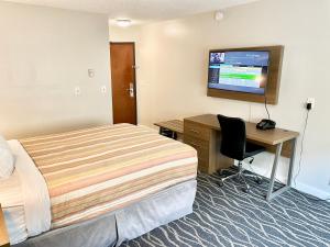 a hotel room with a bed and a desk and a television at Dunes Motel Hillsboro in Hillsboro