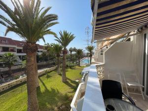 a balcony with palm trees and a swimming pool at Cozy apartment with balcony, pool and Wifi in Playa de Las Americas in Playa de las Americas