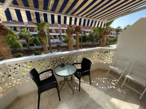 a patio with chairs and a table on a balcony at Cozy apartment with balcony, pool and Wifi in Playa de Las Americas in Playa de las Americas