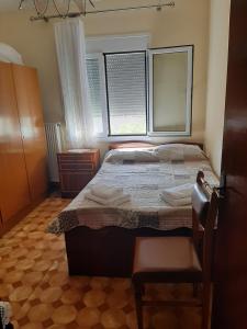 a bedroom with a bed and two windows and a chair at ANNAS COTTAGE in Skala Sotiros