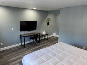 a bedroom with a bed and a desk with a television at Surf City Inn & Suites in Santa Cruz