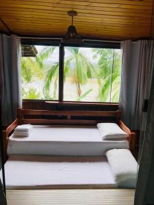 three beds in a room with a window at Pousada Kaetê in Paraty