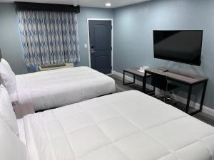 Habitación de hotel con 2 camas y TV de pantalla plana. en Surf City Inn & Suites en Santa Cruz