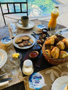 a table with plates of food and a basket of pastries at Maison des Bourgades in Saint-Julien-de-Peyrolas