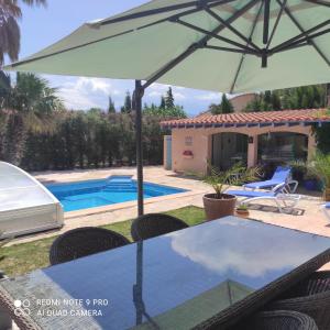 einen Tisch mit einem Sonnenschirm neben einem Pool in der Unterkunft Villa Casaleno gite La Cigale avec wi-fi in Millas