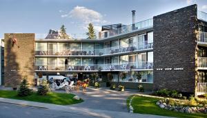 - un grand bâtiment en briques avec des personnes assises sur le balcon dans l'établissement Bow View Lodge, à Banff