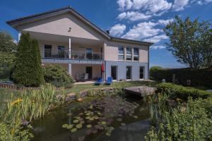 een huis met een vijver ervoor bij Ferienwohnung Schwalbennest in Weinsheim