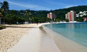 a beach with blue water and buildings in the background at Private 2 Bedroom Beachfront Penthouse Condo Ocho Rios, Jamaica in Ocho Rios