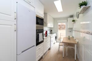 a kitchen with white appliances and a wooden table at La casa de San Martín. Parque Warner, Madrid in San Martín de la Vega