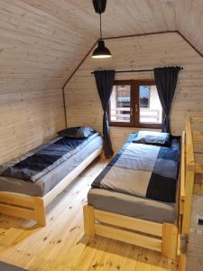 two beds in a room with wooden walls at Domki Pod Dębami in Pobierowo