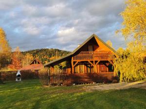 a large wooden house with a deck on a field at Pokoje Gościnne Agnes in Sanok