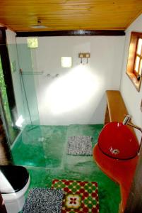 W łazience znajduje się czerwona toaleta i przeszklony prysznic. w obiekcie Pousada Estância Rio Acima w mieście Itamonte
