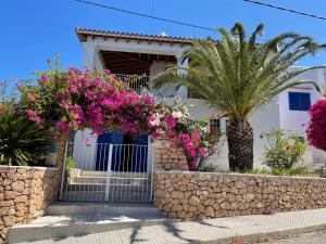 una casa con flores rosas delante de ella en Es Queixal - Can Canet con piscina exterior climatizada, en Cala Vadella