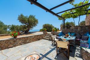 a patio with a table and chairs and a stone wall at Sifnos' Green and Blue in Sifnos