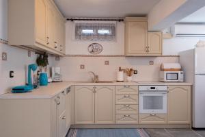 a kitchen with white cabinets and a white refrigerator at Sifnos' Green and Blue in Sifnos +25 photos