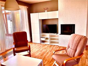 ein Wohnzimmer mit 2 Stühlen und einem TV in der Unterkunft Apartmány Vojta in Telč