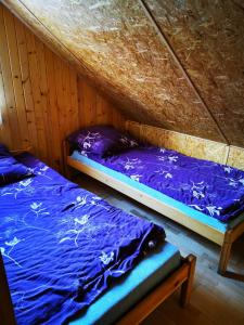 two beds in a wooden room with purple sheets at Pokoje Gościnne Agnes in Sanok