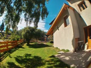 una casa con un patio verde junto a una valla en Alojamiento Turistico Yazaar en San Carlos de Bariloche