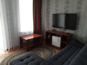 uma sala de estar com um sofá e uma televisão de ecrã plano em Гостиница Караганда em Karaganda