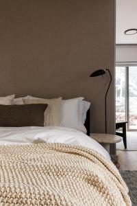 a bedroom with a white bed with a lamp and a window at White Pearl in Hermanus