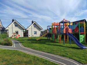 un parque infantil en un patio con casas al fondo en Ośrodek Wypoczynkowy Domki Nadika en Bobolin